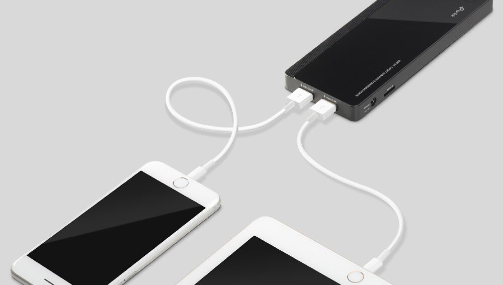 Hub TP-LINK UH720 Widok na tył czarnego urządzenia z podłączonymi dwoma białymi kablami USB, które prowadzą do leżącego obok smartfona i tabletu