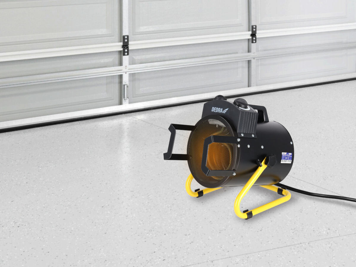 Nagrzewnica elektryczna DEDRA DED9931B, IP24, zachlapania, przegrzanie, długotrwałość, Nagrzewnica DEDRA DED9931B pracuje w jasnym garażu na betonowej podłodze, widoczne żebrowanie.