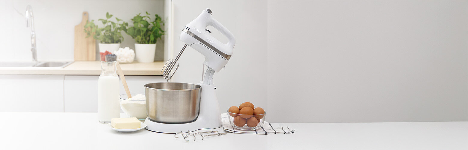 Mikser z misą obrotową MMR-26Z/B na kuchennym blacie, obok składniki do ciasta i mieszadła.