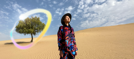 Widoczny od przodu iPad Pro, na ekranie wiele otwartych aplikacji na tle o gradiencie od ciemnoniebieskiego do zielonego. Dłoń trzyma rysik Apple&nbsp;Pencil Pro i zakreśla szkic, używając funkcji różdżki graficznej Apple&nbsp;Intelligence