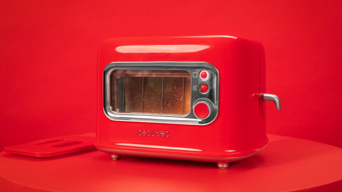 Czerwony toster z przezroczystym panelem, przez który widać opieczone kromki chleba. Na tosterze widoczne jest logo \'CECOTEC\'.