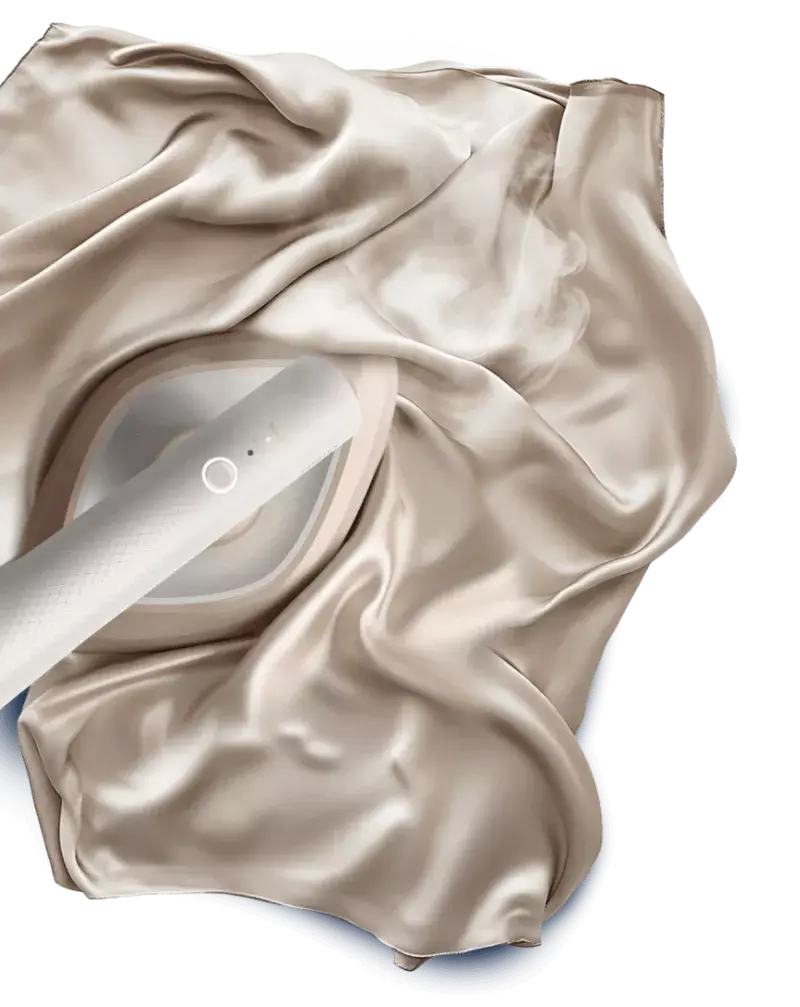 Na obrazie widać parownicę do ubrań, która jest używana na gładkiej, jasnej tkaninie. Parownica emituje parę, co sugeruje jej działanie.