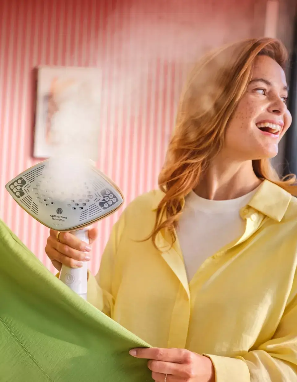 Osoba trzyma parownicę do ubrań, z której wydobywa się para. Na urządzeniu widoczny jest napis \'OptimalTemp technology\'.