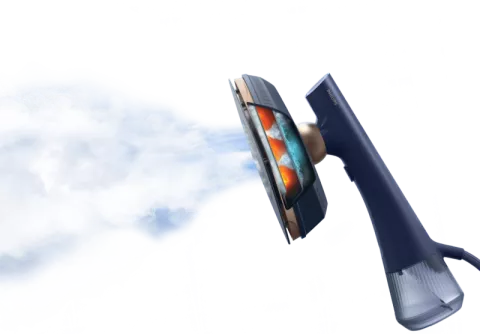 Na obrazie widoczna jest parownica do ubrań, z której wydobywa się strumień pary. Urządzenie ma ciemny uchwyt i przezroczysty zbiornik na wodę.