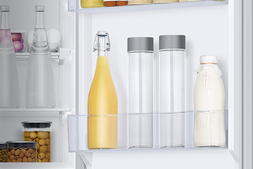 Sok, butelki wody i mleko na półkach drzwiowych