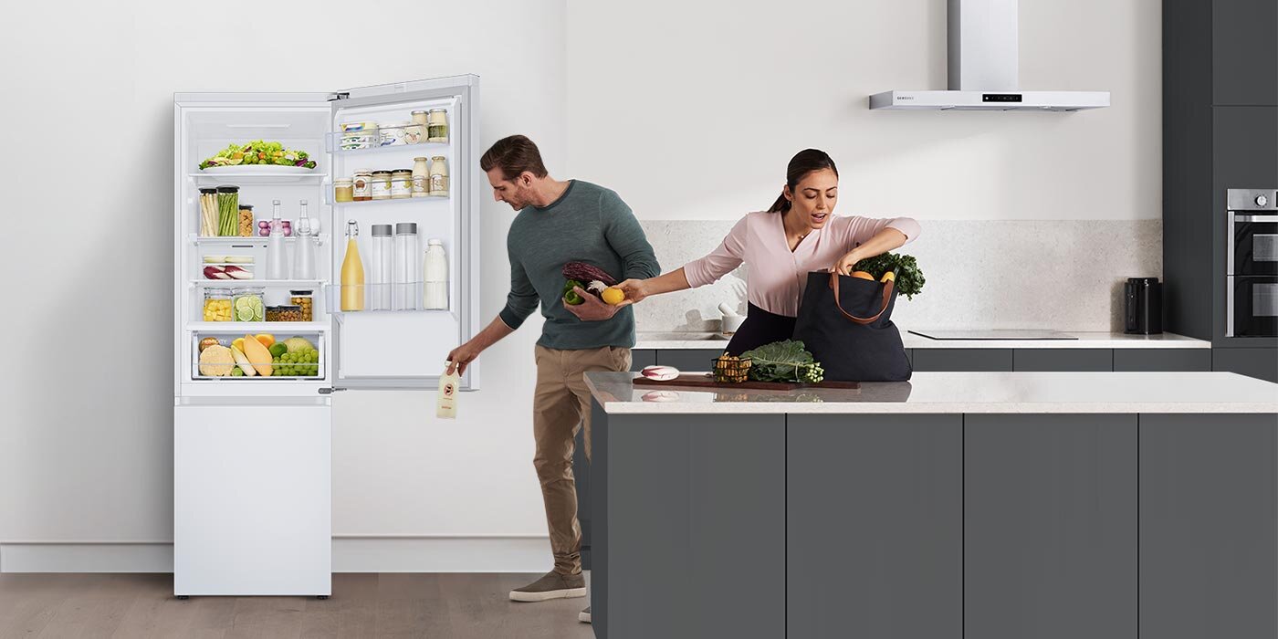 Para wypakowująca zakupy z płóciennej torby do lodówki