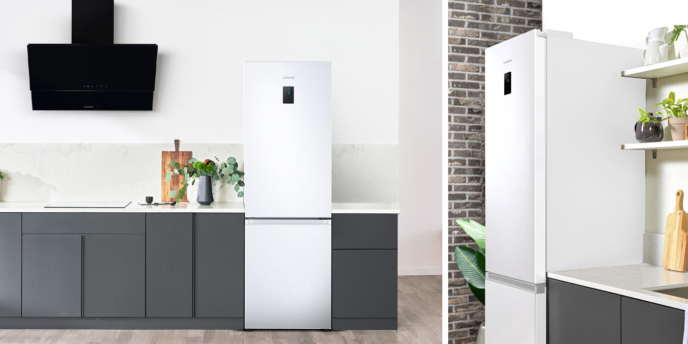 Biała lodówka w kuchni z szarymi szafkami kuchennymi. Pokazana od frontu i z półprofilu