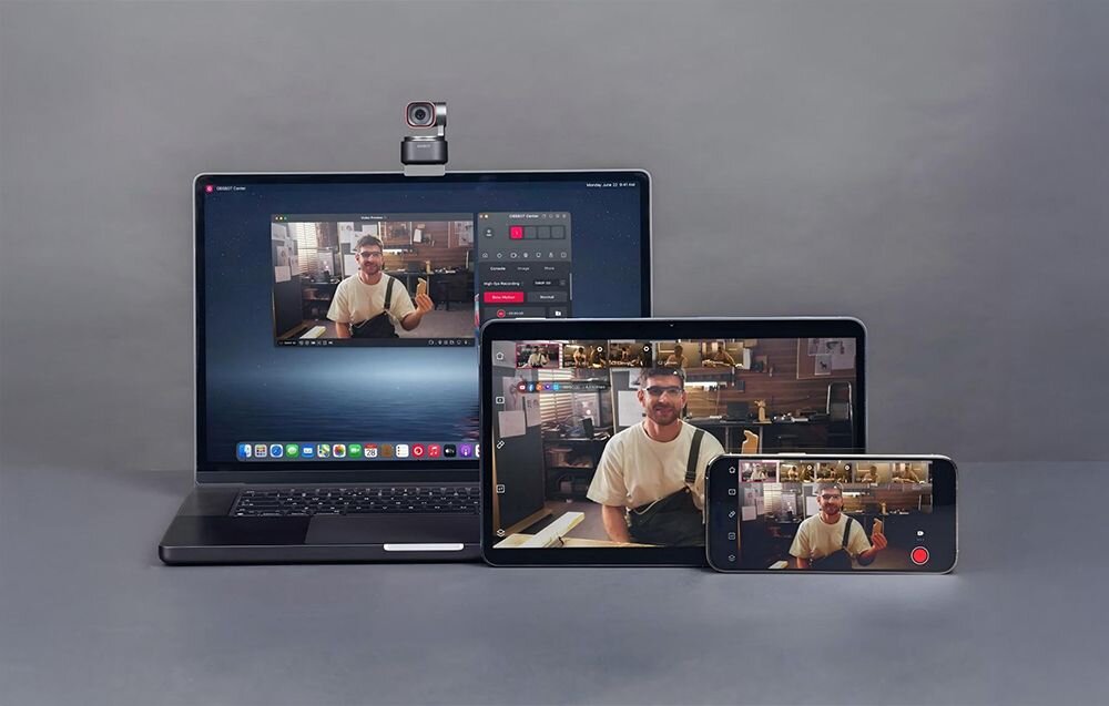 Na obrazie widać laptopa, tablet i smartfon, na których wyświetlany jest ten sam obraz mężczyzny siedzącego przy biurku. Na laptopie zamontowana jest kamera internetowa.