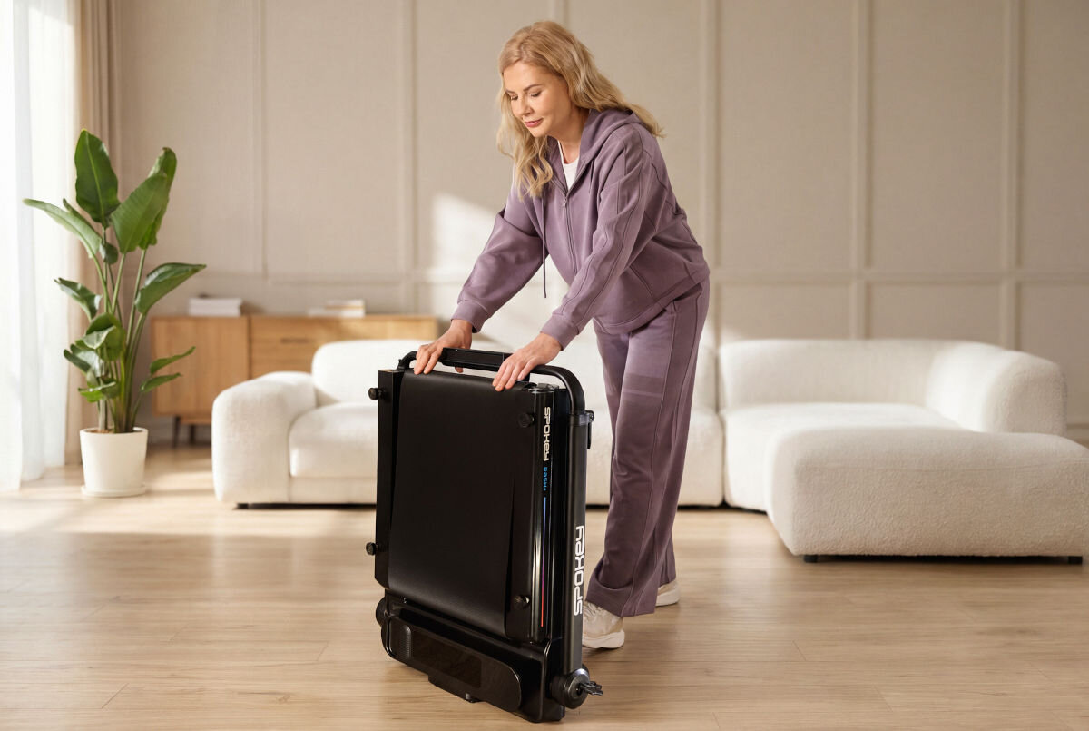 Bieżnia elektryczna SPOKEY Dash+ 932W 6 km/h, przenoszenie, łatwość, mobilność, wygoda, Kobieta składa bieżnię Spokey do pionowego przechowywania