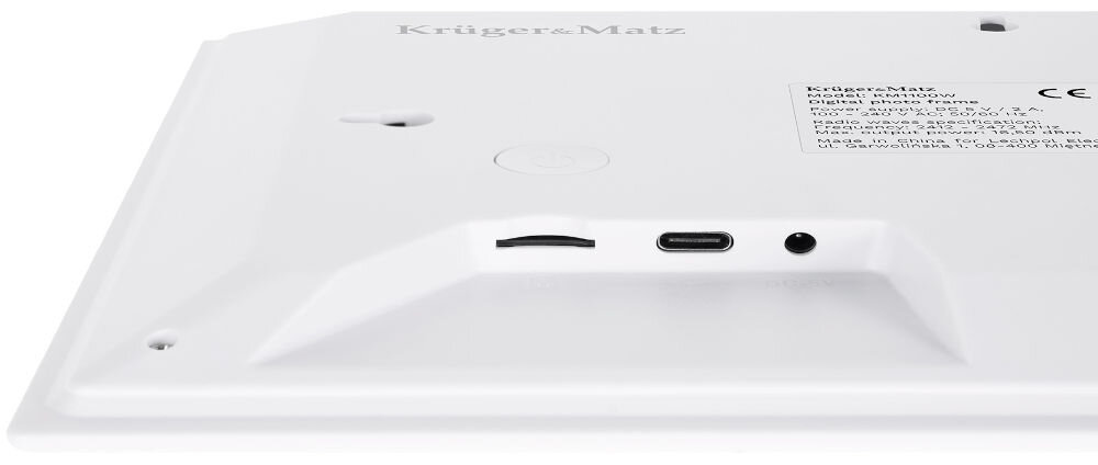 Biała tylna część ramki cyfrowej z widocznymi portami: slot na kartę pamięci, port USB-C i gniazdo audio. Na powierzchni znajduje się logo \'Krüger&Matz\' oraz naklejka z informacjami technicznymi.