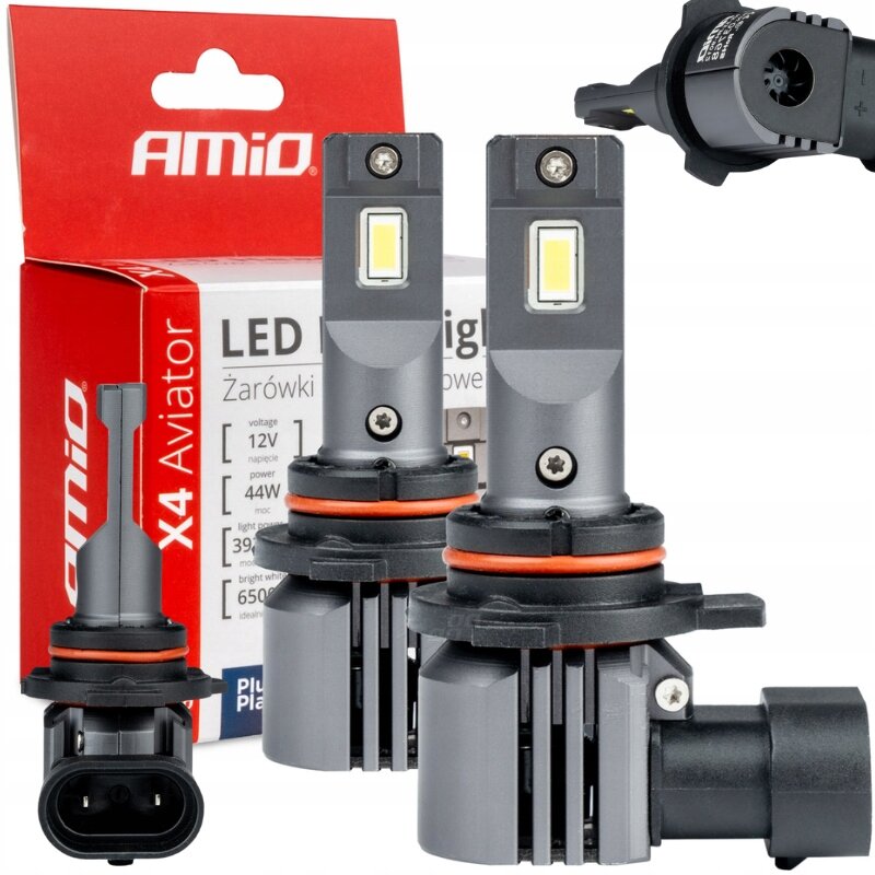 Na obrazie widoczne są dwie szare żarówki LED z pomarańczowymi uszczelkami oraz opakowanie z logo \'AMiO\'. Na opakowaniu znajduje się tekst: \'LED X4 Aviator Żarówki Samochodowe\'.