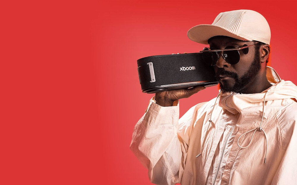 Głośnik mobilny LG Bounce charakterystyczne brzmienie xboom will.i.am, osoba trzymająca głośnik na czerwonym tle