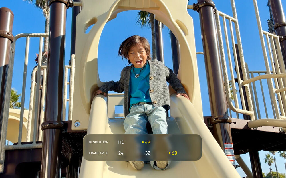 Smartfon APPLE iPhone 17e Ekran iPhone'a rejestrujący wideo bawiącego się dziecka na zjeżdżalni. Na dole widoczne menu ustawień wideo z wybraną rozdzielczością 4K oraz płynnością 60 klatek na sekundę (fps).