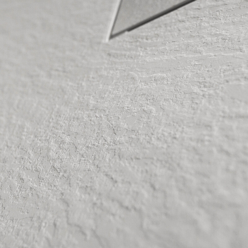 Zbliżenie na białą, teksturowaną powierzchnię z widocznym fragmentem metalowego elementu w rogu.