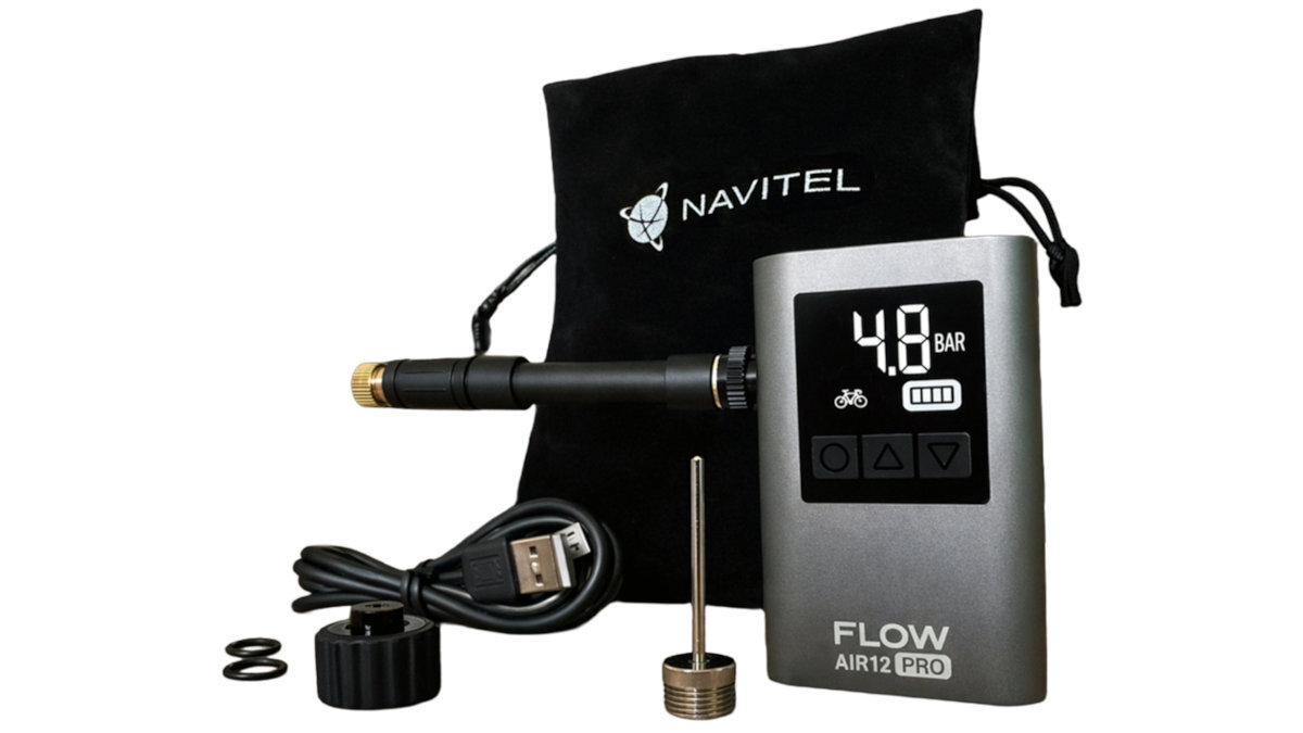 Na zdjęciu znajduje się pompka rowerowa z wyświetlaczem pokazującym 4.8 BAR, obok której leży kabel USB, igła, adapter oraz czarna torba z logo NAVITEL. Na pompce widnieje napis \'FLOW AIR12 PRO\'.