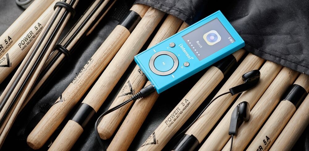 Odtwarzzacz MP3 INTENSO 64GB Video Scooter Bluetooth bezprzewodowe słuchawki połączenie z komputerem, słuchawki podłączone do odtwarzacza leżące na pałeczkach do perkusji