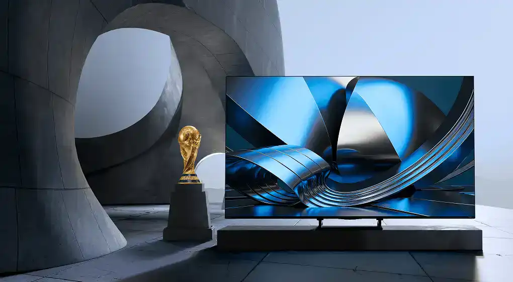 Telewizor z niebieską grafiką obok Pucharu Świata FIFA na postumencie, umieszczony w szarym wnętrzu z betonowymi łukami
