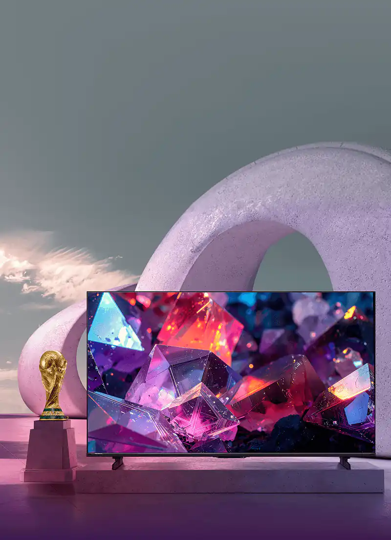 Telewizor Hisense E7 Pro z kolorową grafiką kryształów obok statuetki FIFA World Cup na tle betonowych, owalnych łuków.