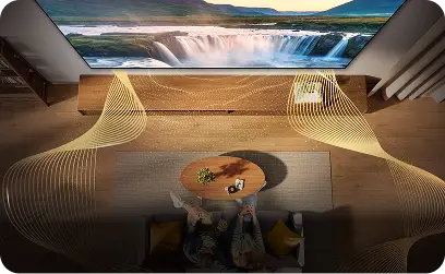 Widok z góry na parę na kanapie; złote fale wokół telewizora symbolizują dźwięk przestrzenny Dolby Atmos