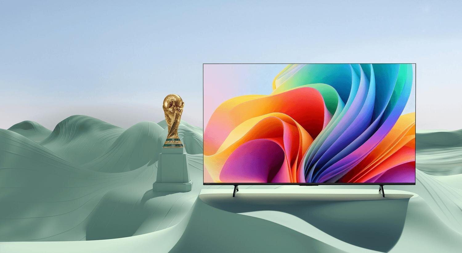 Telewizor z grafiką obok pucharu FIFA (Federation Internationale de Football Association) na tle zielonych wzgórz