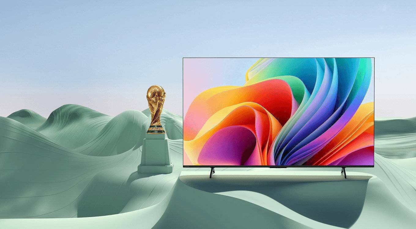 Telewizor z grafiką obok pucharu FIFA (Federation Internationale de Football Association) na tle zielonych wzgórz