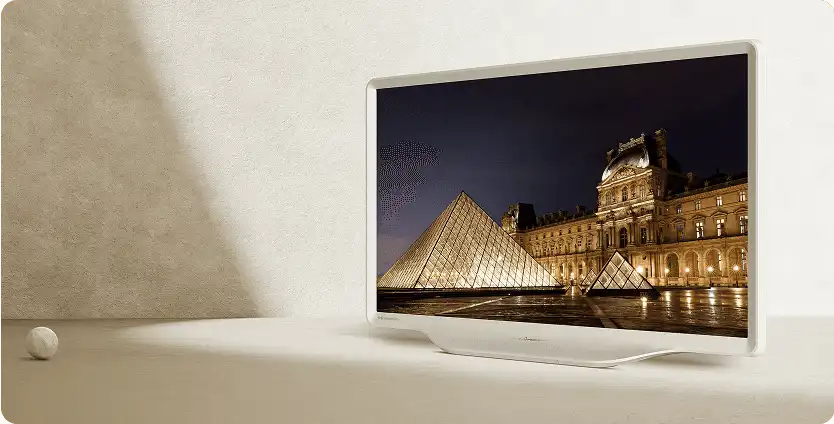 Telewizor Hisense S5 w białej obudowie w minimalistycznym jasnym pomieszczeniu wyświetla wyraźne nocne zdjęcie muzeum Luwr