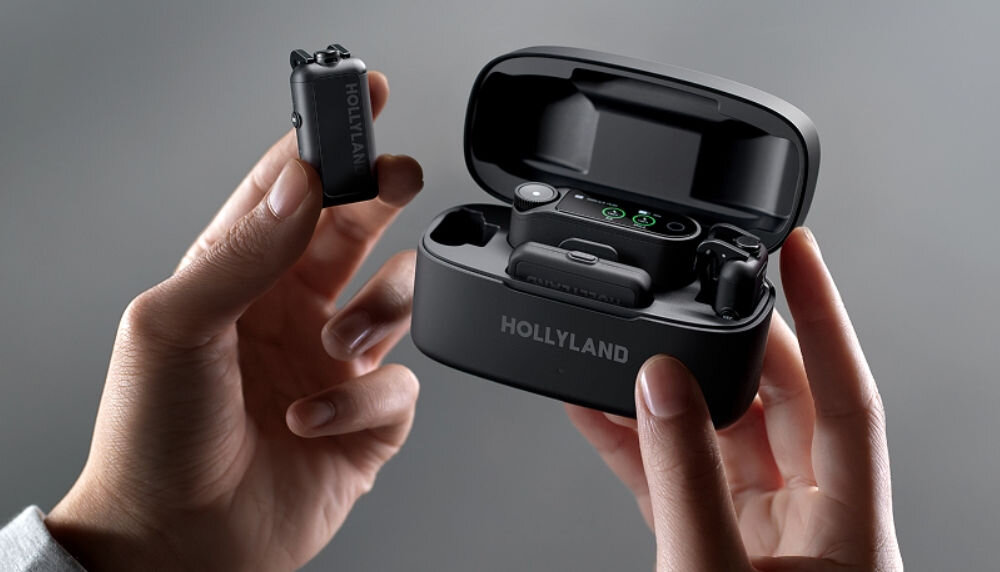 System bezprzewodowy HOLLYLAND Lark Max 2 Ultimate Combo Osoba otwiera pudełko mikrofonu MAX 2 i wyjmuje nadajnik, na szarym tle czas pracy wersja z etui ładującym ma wydłużony czas pracy port USB-C