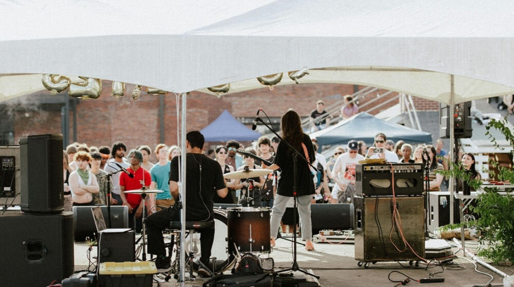 System bezprzewodowy HOLLYLAND Lark Max 2 Ultimate Combo Zespół gra na scenie, a przed nimi stoi wielu widzów technologia przeskoku częstotliwości niskie opóźnienie 20 ms