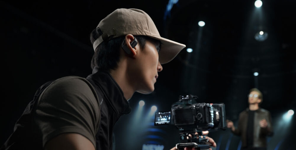 System bezprzewodowy HOLLYLAND Lark Max 2 Ultimate Combo Mężczyzna w czapce z daszkiem, z mikrofonem MAX 2, nagrywa w studiu technologia przeskoku częstotliwości 2.4 GHz stabilne krystalicznie czyste audio niskie opóźnienie 25 ms 18 godzin pracy na baterii słuchawka Bluetooth