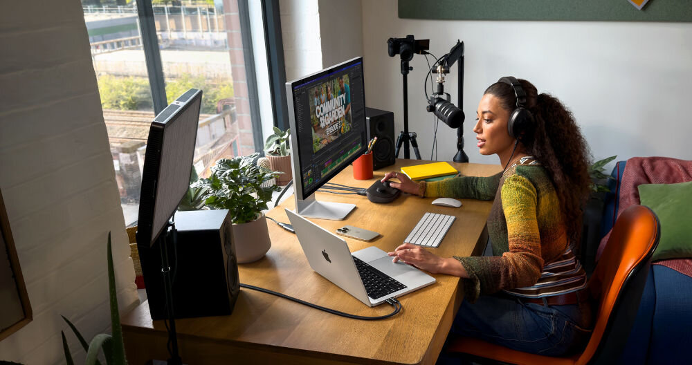 Laptop APPLE MacBook Pro 2026 Kobieta w domowym studiu edytująca wideo na komputerze Mac z dodatkowym monitorem, mikrofonem profesjonalnym i oświetleniem studyjnym.