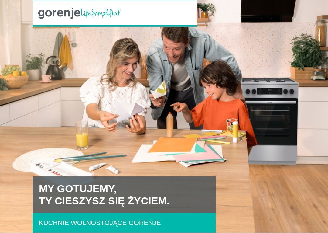 KUCHNIA GORENJE MEKS5141XM Rodzina złożona z dwóch dorosłych i dziecka spędza czas przy kuchennym stole, wycinając kolorowe elementy z papieru, w tle widoczna jest zabudowa kuchenna z kuchnią wolnostojącą Gorenje, a u dołu znajduje się napis „MY GOTUJEMY, TY CIESZYSZ SIĘ ŻYCIEM. KUCHNIE WOLNOSTOJĄCE GORENJE”