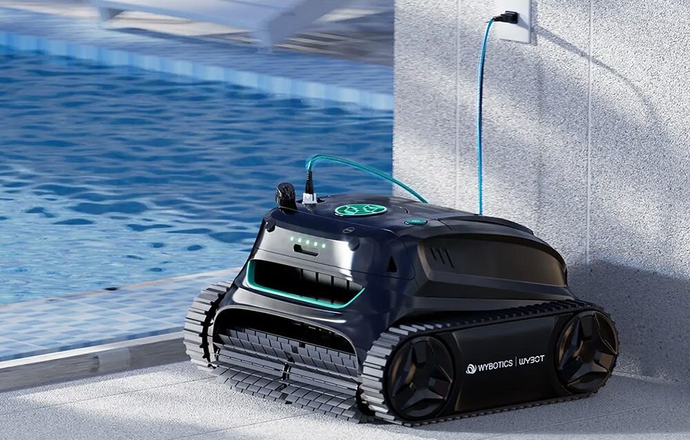 Na zdjęciu widać robota do czyszczenia basenów z logo \'WYBOTICS\' i \'WYBOT\'. Robot jest podłączony do gniazdka elektrycznego i znajduje się przy basenie z niebieską wodą.