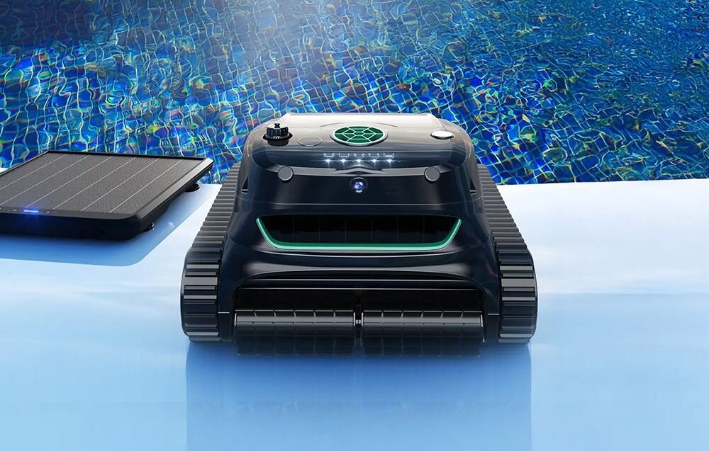 Na zdjęciu widać czarny robot do czyszczenia basenów z zielonymi elementami, umieszczony na brzegu basenu. Obok robota znajduje się panel słoneczny.