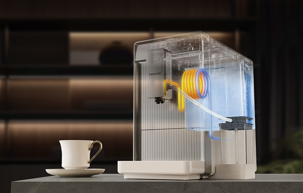 Na obrazie znajduje się ekspres do kawy z przezroczystą obudową, ukazującą wewnętrzne elementy, takie jak kolorowe rurki. Obok ekspresu stoi filiżanka na blacie.