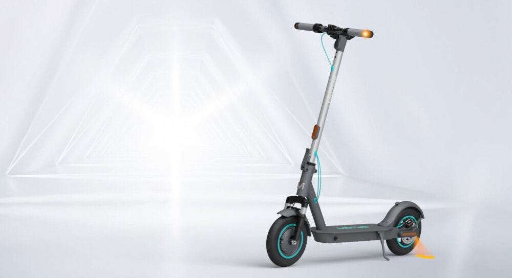 Hulajnoga elektryczna MOTUS Scooty 10 Lite Gen 6 30km 350W Amortyzacja 10 cali Szary hulajnoga widoczna z boku zdjęcie na szaro-białym abstrakcyjnym tle do jazdy po mieście dynamiczne ekscytujące podróżowanie szereg udogodnień praktyczne rozwiązania system KERS kierunkowskazy składana konstrukcja styl moc wygoda