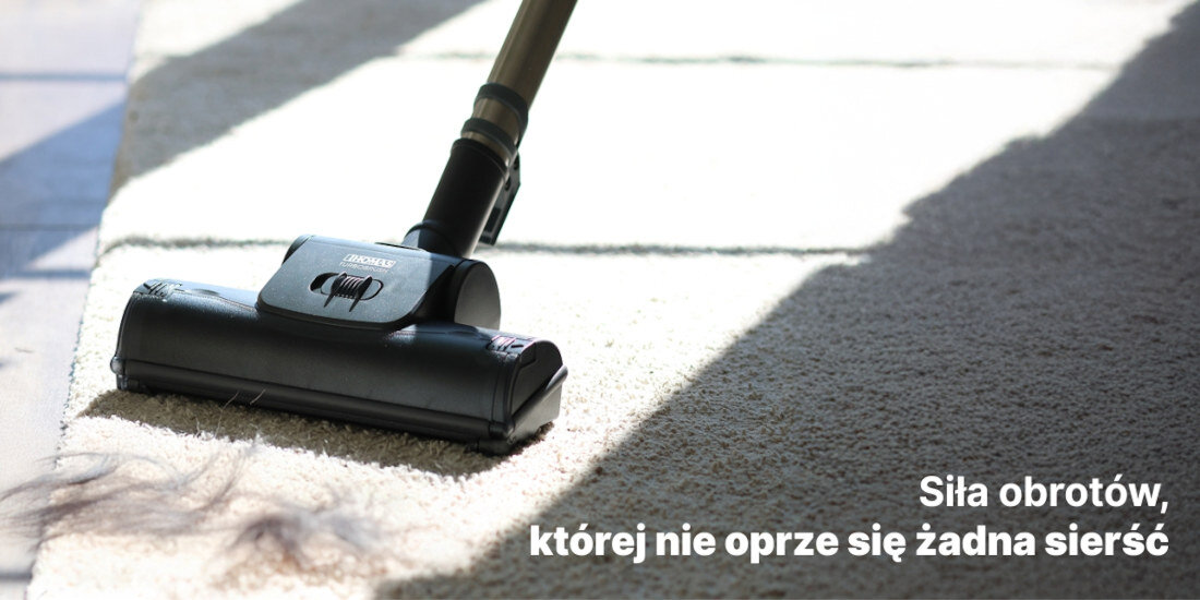 Odkurzacz piorący na dywanie z widocznymi włosami. Tekst na obrazie: \'Siła obrotów, której nie oprze się żadna sierść\'.
