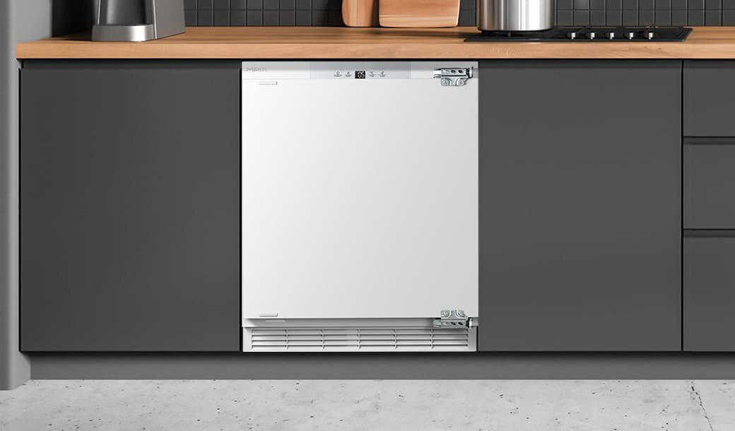 Lodówka MPM-116-CJI-17/E w ciemnej zabudowie kuchennej.