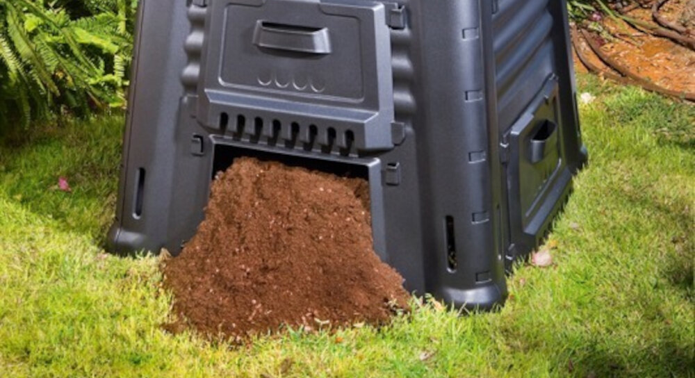 Kompostownik KETER Mega composter 650 l Czarny zbliżenie na dolny otwór z wysypującą się ziemią pojemność 650 litrów gromadzenie dużej ilości odpadów organicznych ekologiczny kompost dolny otwór łatwy dostęp do gotowego kompostu