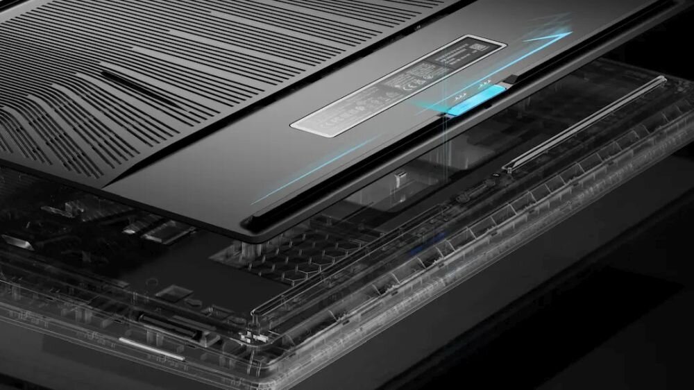 Obraz przedstawia otwarty laptop z widocznym systemem chłodzenia i wentylacją na spodzie obudowy. Na obudowie znajduje się naklejka z informacjami technicznymi.