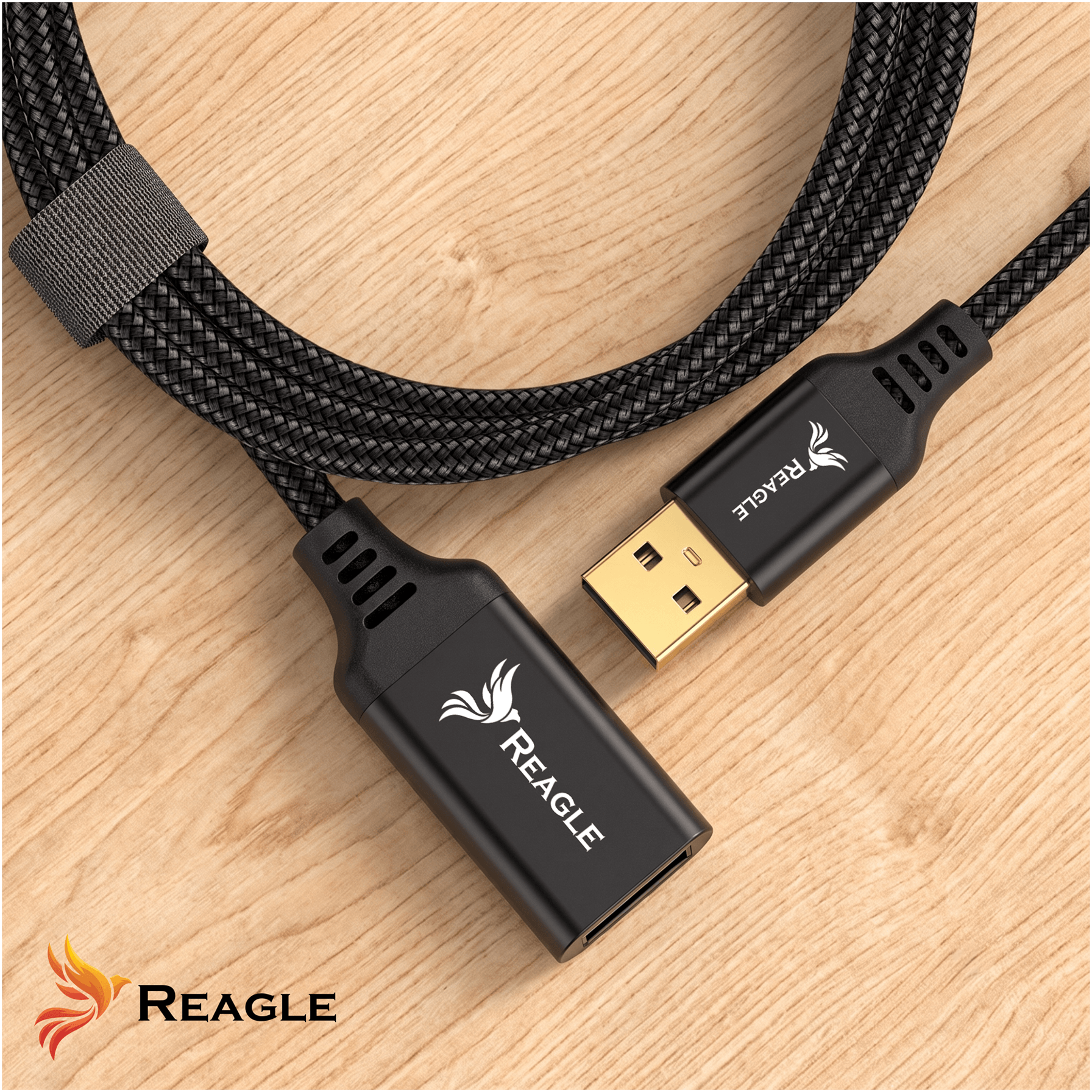Na drewnianej powierzchni leży czarny, pleciony kabel USB z logo Reagle na obu końcówkach. Jedna końcówka ma złącze USB-A, a druga jest gniazdem USB-A.