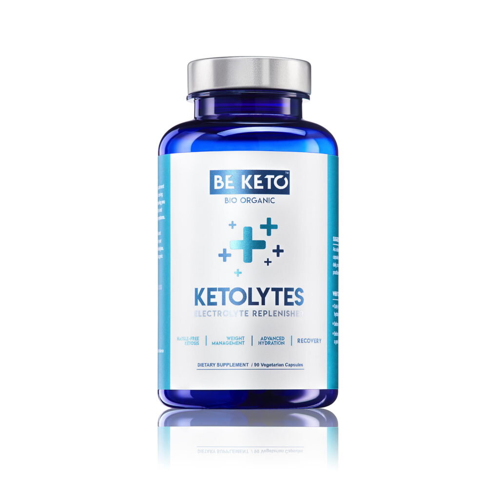 Niebieska butelka z białą etykietą zawiera napis \'BE KETO BIO ORGANIC KETOLYTES ELECTROLYTE REPLENISH\'. Na etykiecie widoczne są symbole plusów oraz informacje o właściwościach produktu, takich jak \'WEIGHT MANAGEMENT\' i \'ADVANCED HYDRATION\'.