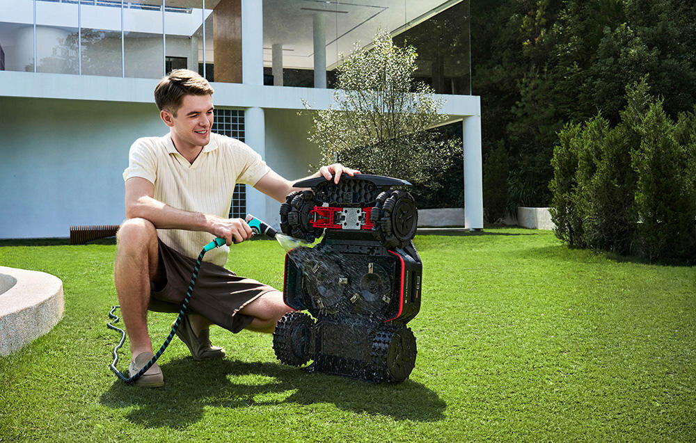 Robot koszący DREAME A3 AWD Pro 5000 ogród osoba myje robota w tle dom klasa wodoodporności IPX6 bezproblemowe spłukiwanie utrzymuje urządzenie w czystości w optymalnej kondycji technicznej wygoda oszczędność czasu stała wysoka jakość koszenia