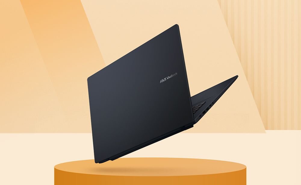 Czarny laptop z widocznym logo \'ASUS Vivobook\' na pokrywie, ustawiony na okrągłej podstawie w jasnym, minimalistycznym otoczeniu.