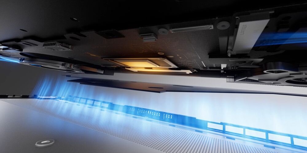 Obraz przedstawia wnętrze laptopa z widocznymi elementami elektronicznymi i podświetleniem w kolorze niebieskim. Widać również otwory wentylacyjne na obudowie.