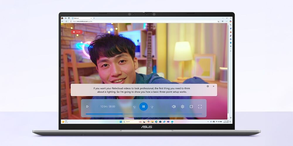 Na ekranie laptopa ASUS wyświetlany jest film z mężczyzną w pokoju, z tekstem: \'If you want your Reolook video to look professional, the first thing you need to think about is lighting. So I\'m going to show you how a basic three-point setup works.\'