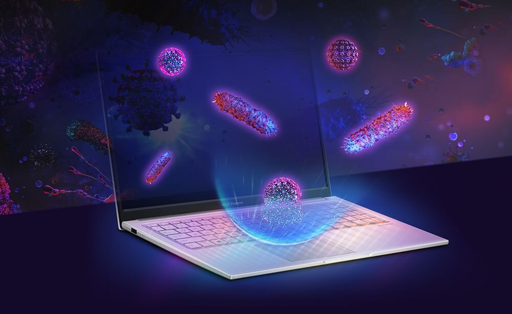 Laptop z otwartym ekranem, na którym widoczne są kolorowe, abstrakcyjne kształty przypominające mikroorganizmy. Klawiatura jest podświetlona, a całość utrzymana w ciemnej, futurystycznej kolorystyce.
