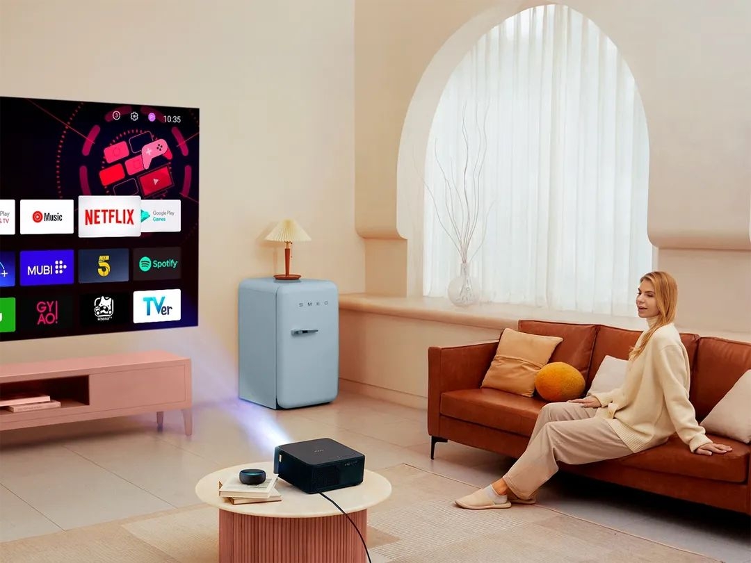 Projektor YABER KS2 Plus - Obraz 800 ANSI i 1080p, natywna rozdzielczość Full HD, 4K HDR, projektor wyświetlający obraz na ścianie, osoba siedząca na kanapie