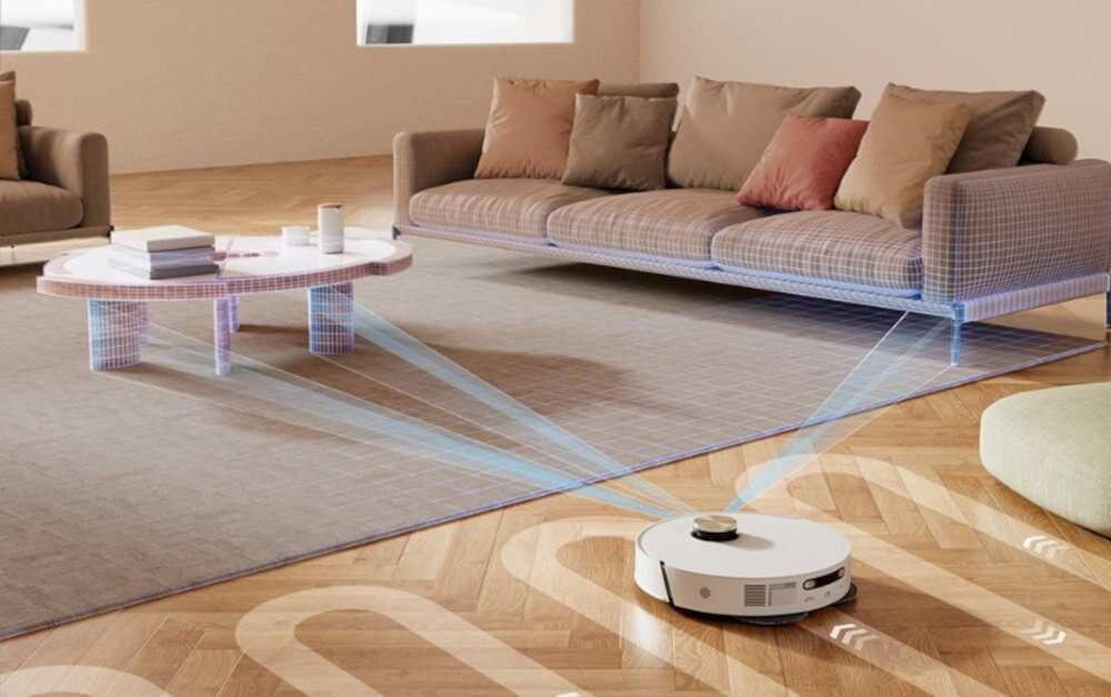 Robot sprzątający porusza się po drewnianej podłodze w salonie, emitując niebieskie linie wskazujące nawigację. W tle znajduje się sofa z poduszkami i niski stolik na dywanie.