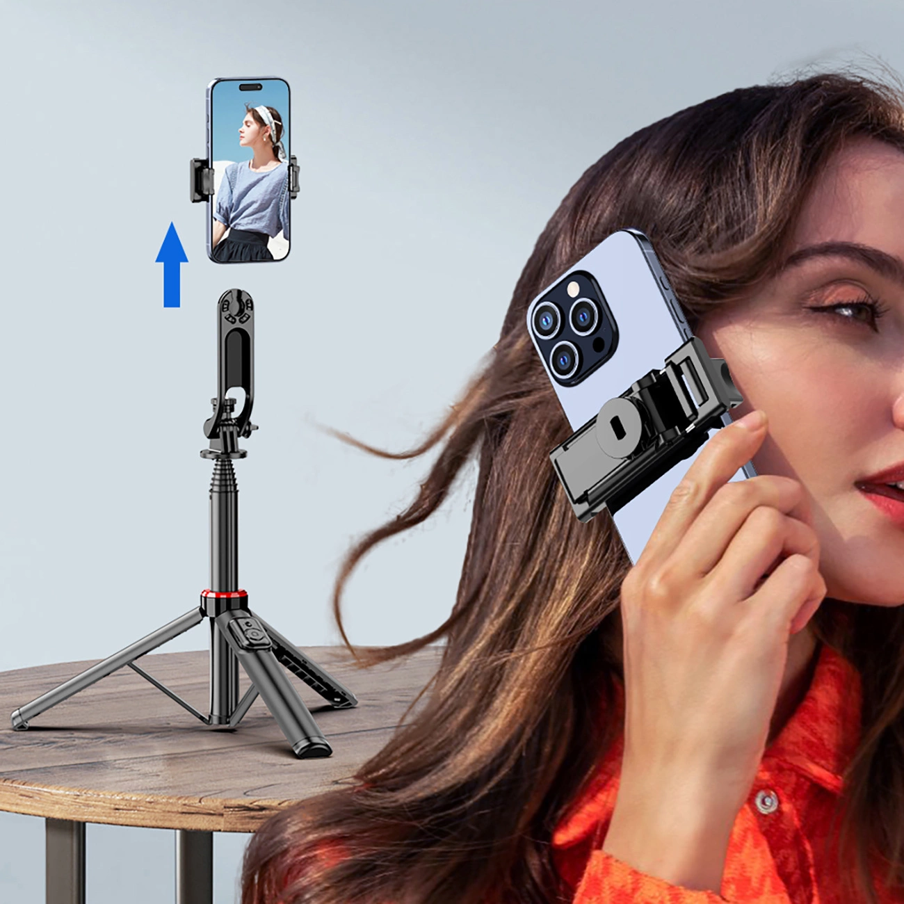 Na obrazie widoczny jest czarny teleskopowy tripod z uchwytem na telefon, ustawiony na stole. Obok znajduje się osoba trzymająca telefon w uchwycie, a na ekranie telefonu widoczna jest postać kobiety.