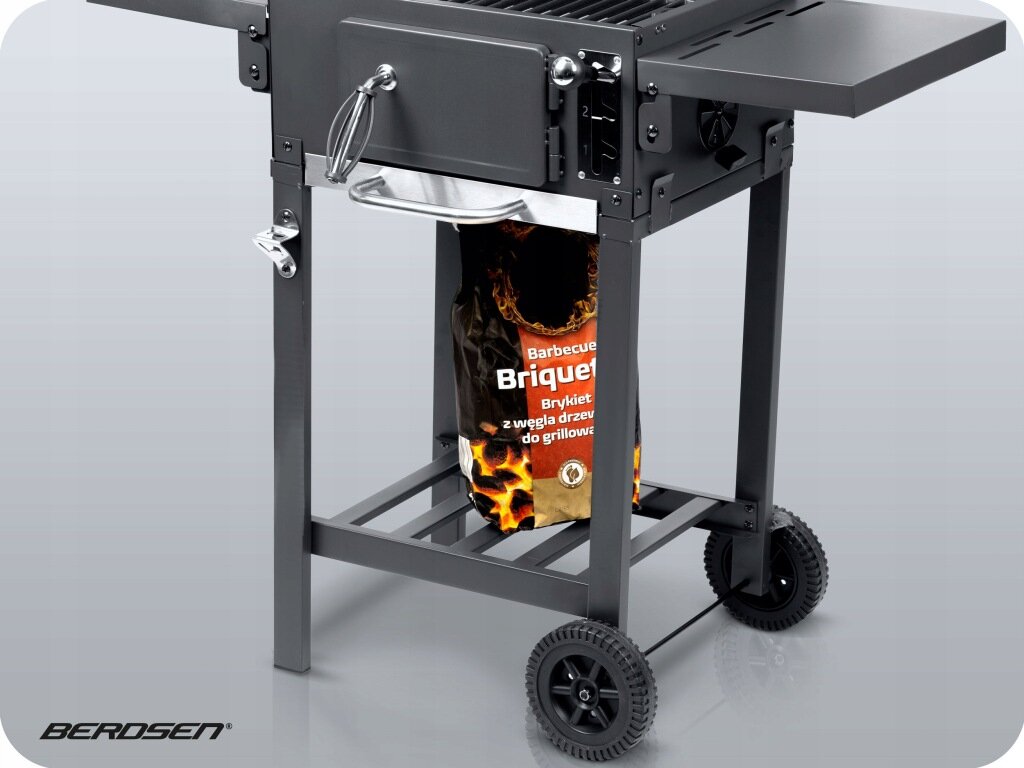 Grill węglowy na kółkach z metalową konstrukcją i boczną półką. Widoczna jest torba z brykietem z napisem \'Barbecue Briquet Brykiet z węgla drzewnego do grillowania\'.